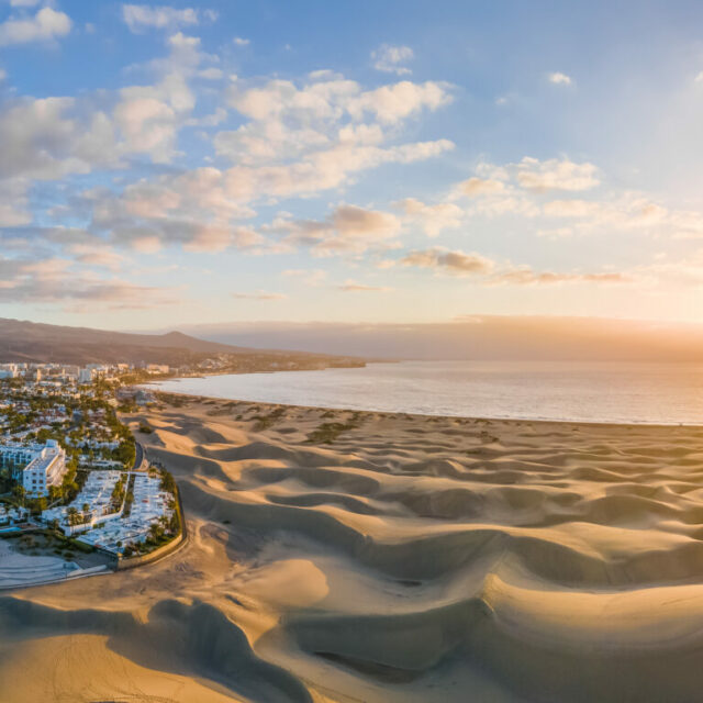 Landscape with Maspalomas town and golden sand dunes at sunrise,