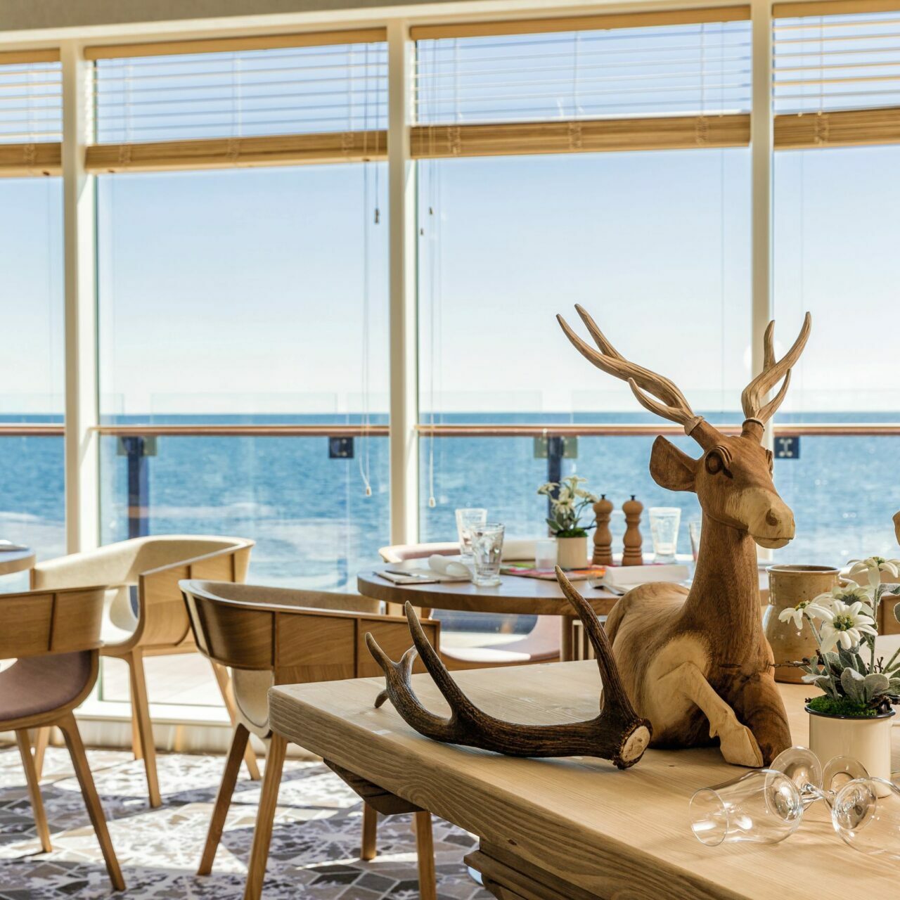 TUI Cruises Mein Schiff Restaurant, zwei Hirsche aus Holz auf dem Tisch, Blick aufs Meer