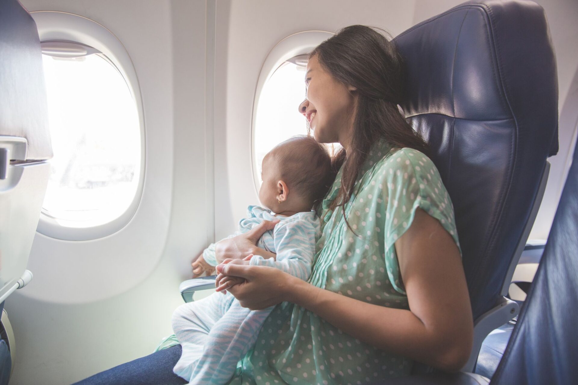 Asiatische Mutter und Baby Fensterplatz im Flugzeug, Fliegen mit Baby