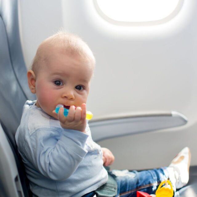 Baby auf Sitz im Flugzeug mit Beißring