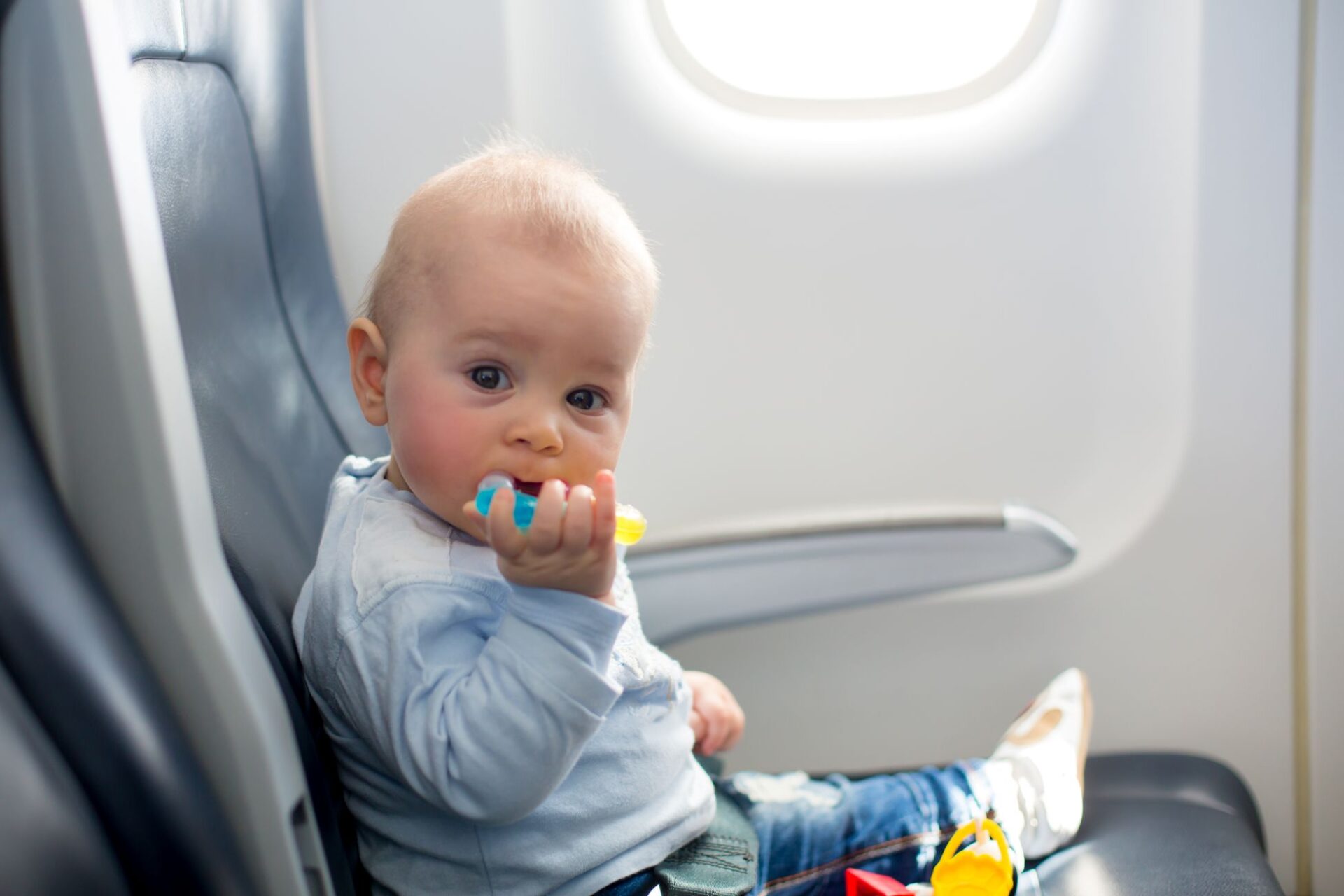 Baby auf Sitz im Flugzeug mit Beißring