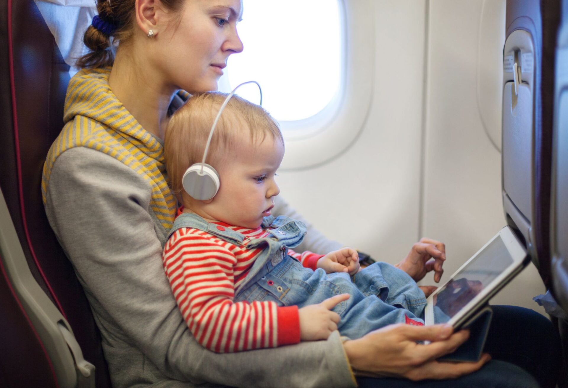 Mutter mit Kleinkind und Tablet im Flugzeug